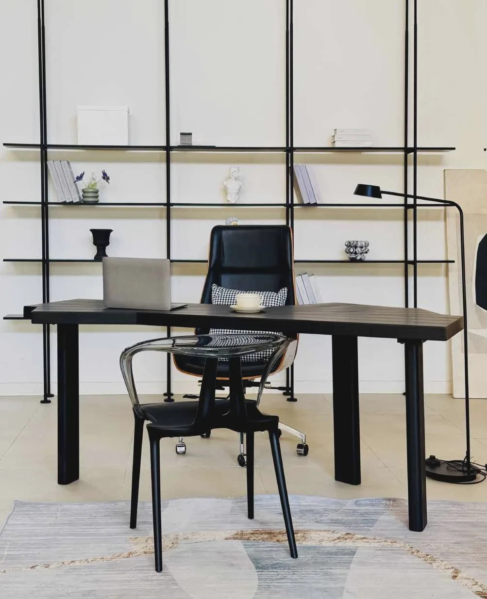 Minimal office setting with a black shelving system, desk and meeting chairs