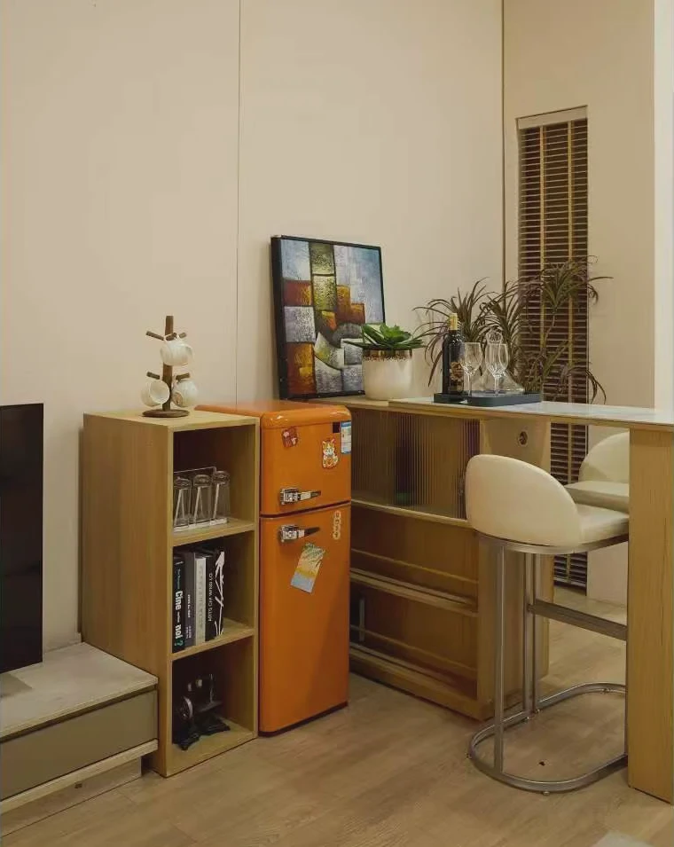 Compact apartment corner with an orange refrigerator, bar counter and storage