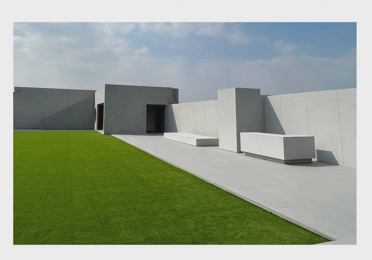 Minimal concrete architecture and geometric walls beside an open rooftop lawn