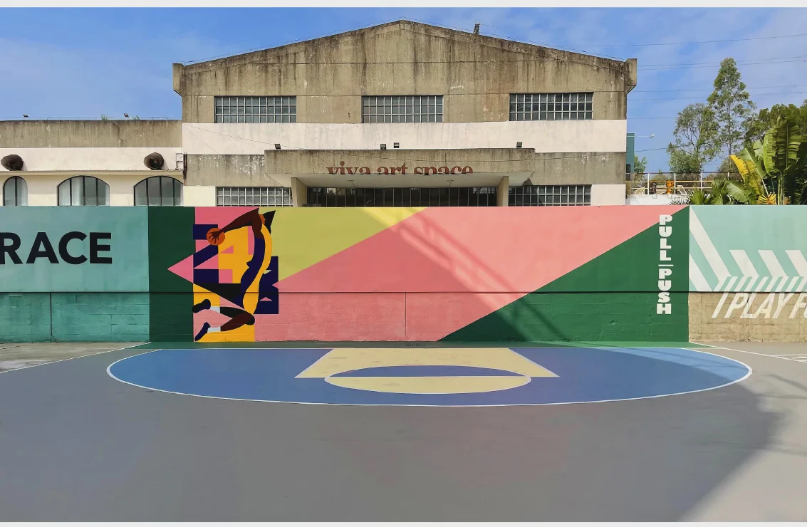 Outdoor sports court with colourful murals in front of an industrial building