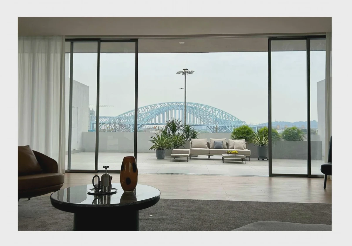 Open view from a living room across a city terrace towards a bridge