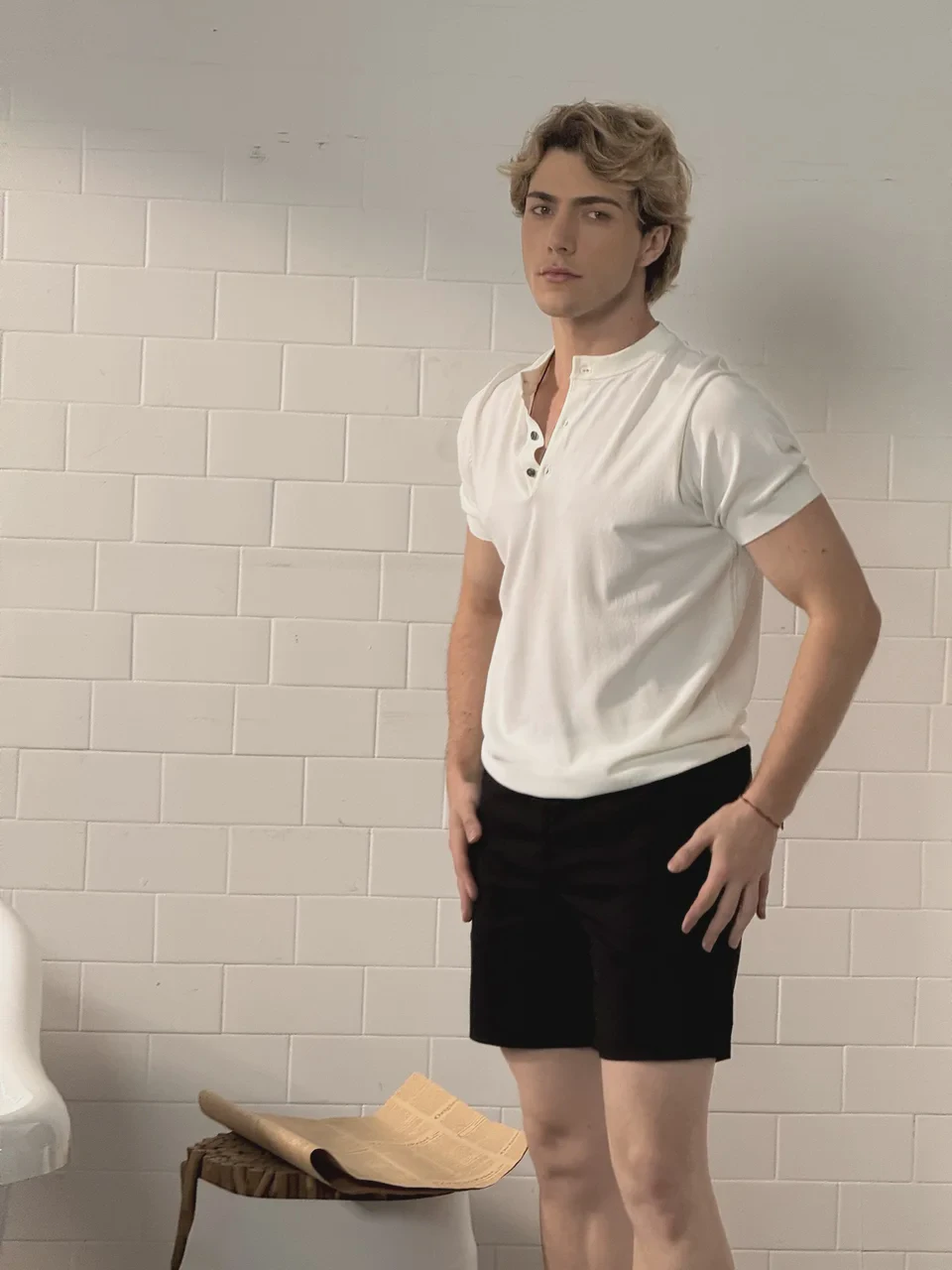 Model in a white top standing before a pale wall, illustrating a portfolio portrait